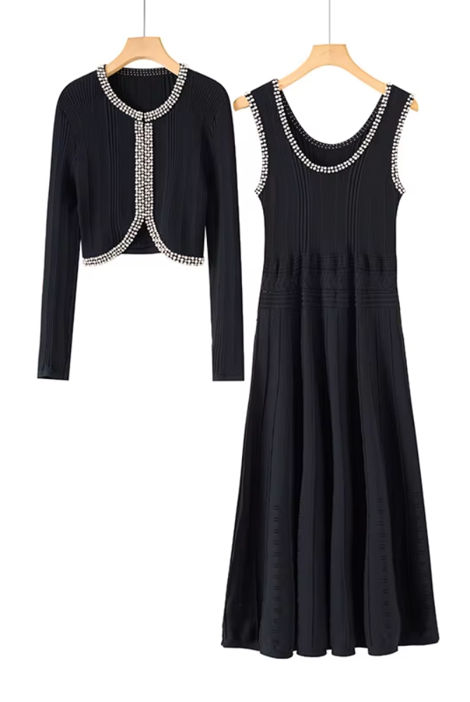 A black two-piece women's outfit set on wooden hangers, featuring a long-sleeve cropped cardigan and a matching sleeveless midi dress with silver rhinestone trim.
