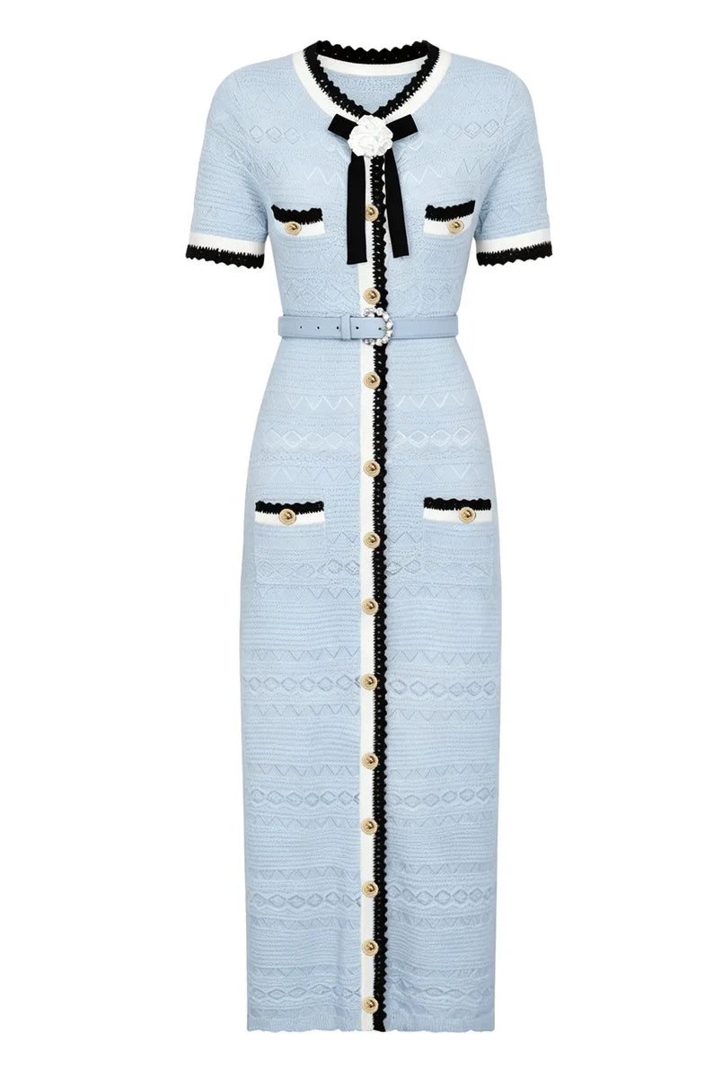 A light blue textured tweed midi dress with black and white trim, featuring a black bow at the collar, gold-tone buttons down the front, and flap pockets with black trim.