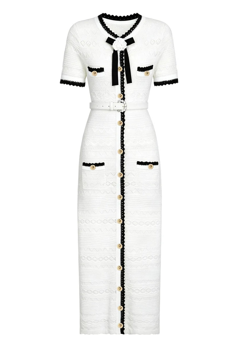 A white tweed midi dress with black trim and gold-tone accents, featuring short sleeves, a black bow at the collar, and a front button closure.