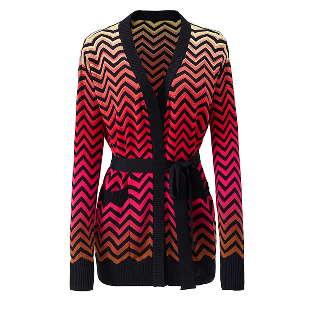 A women's long-sleeve knit cardigan with a V-neck and self-tie belt, featuring a bold chevron zigzag pattern in black, red, pink, and beige, shown against a plain white background.
