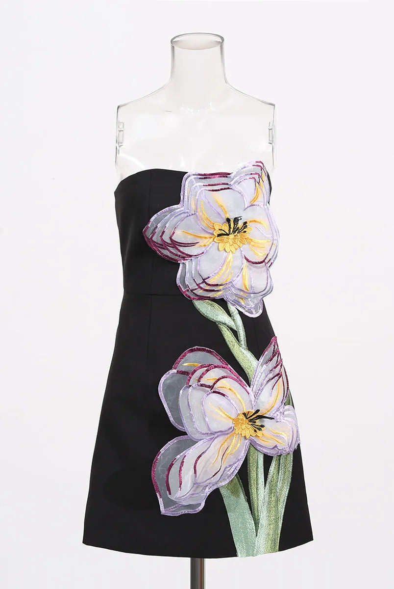 Black dress with floral designs on a mannequin against a white background