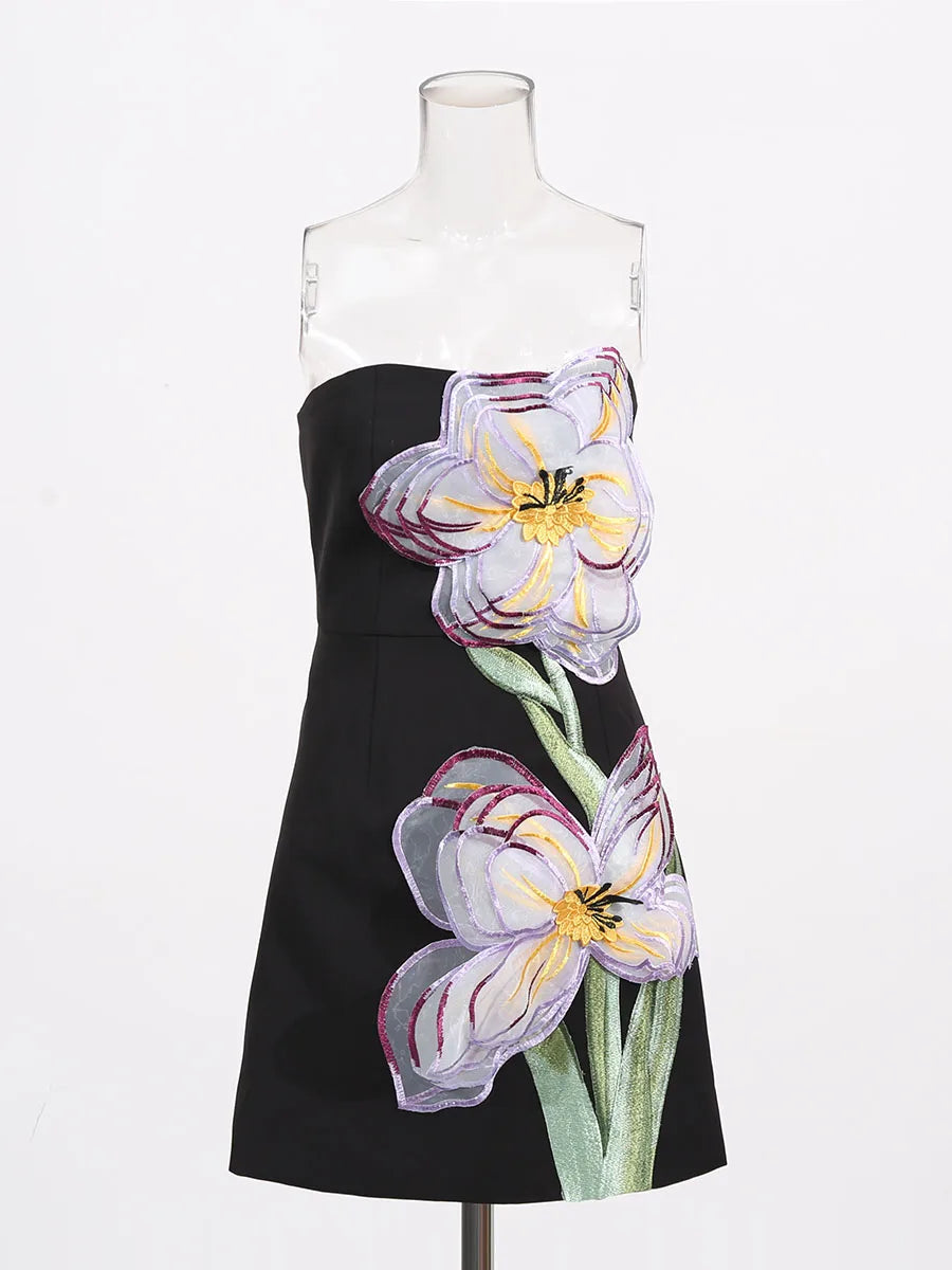 Black dress with floral designs on a mannequin against a white background