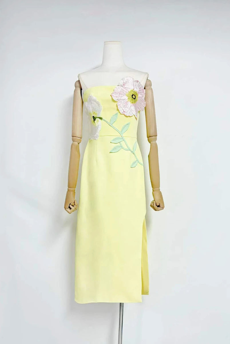 Yellow dress with floral design on a mannequin against a white background