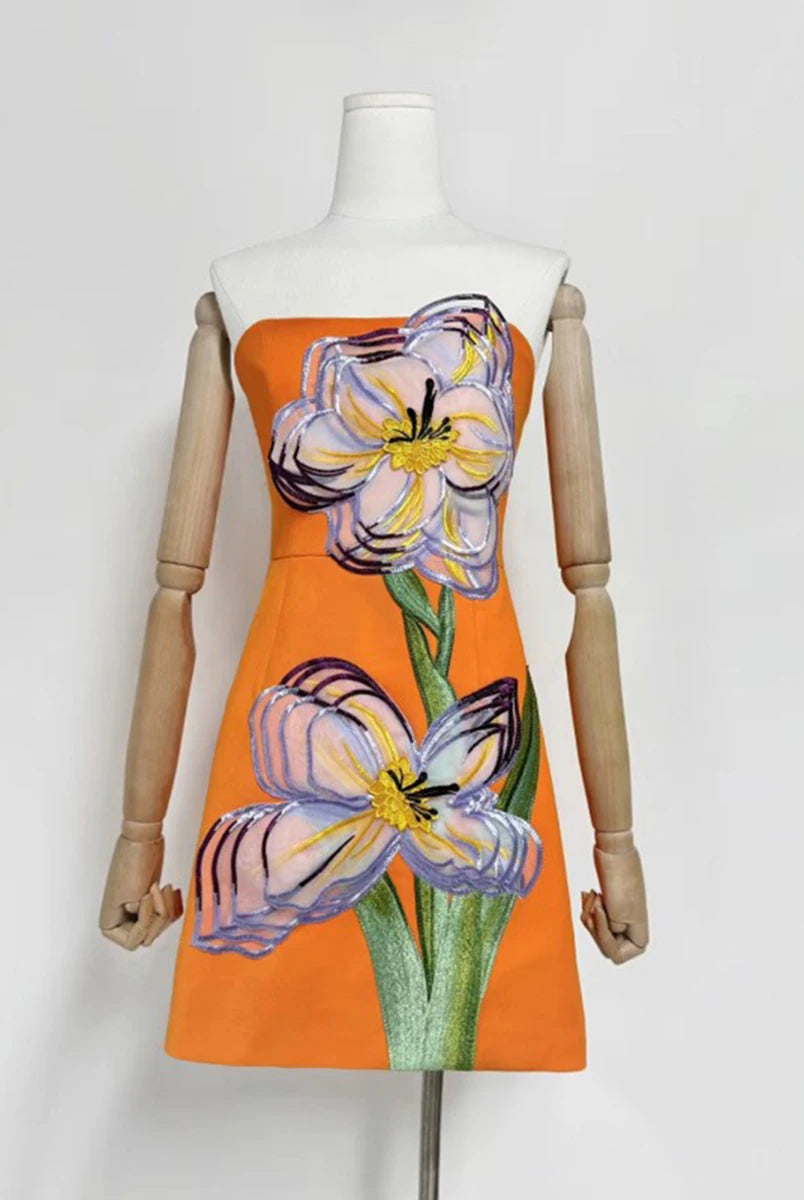 Orange dress with floral design on a mannequin against a white background