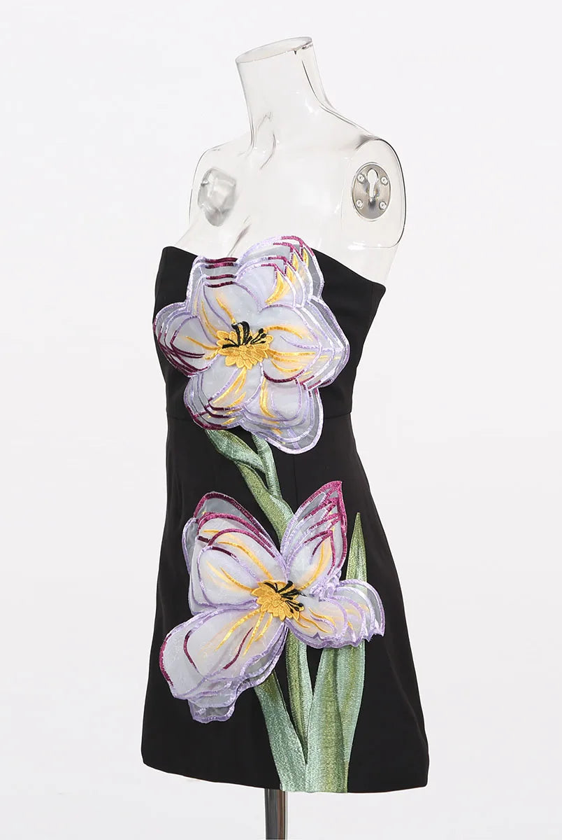 Black dress with floral designs on a mannequin against a white background
