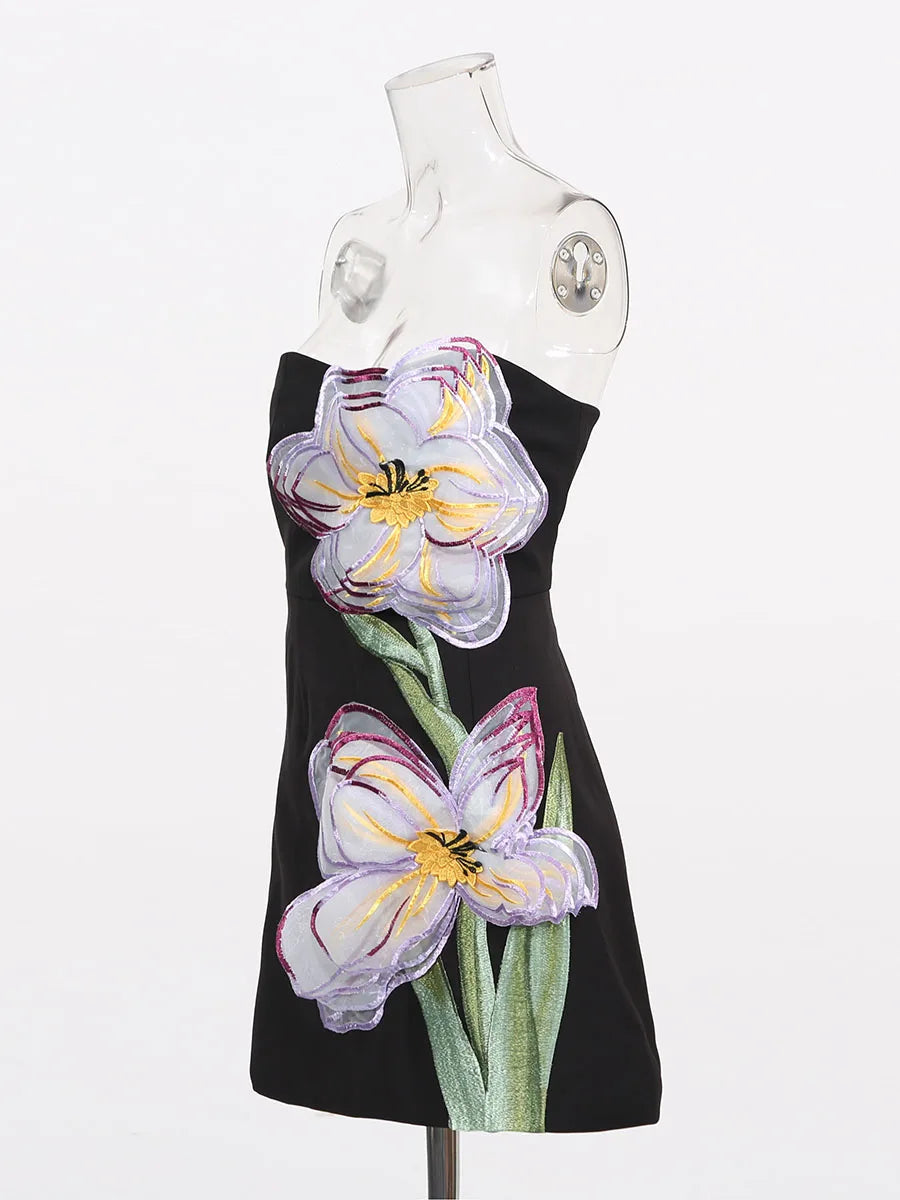 Black dress with floral designs on a mannequin against a white background