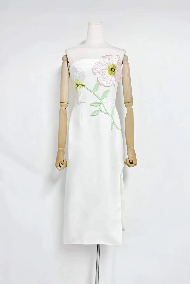 White dress with floral embroidery on a mannequin against a white background