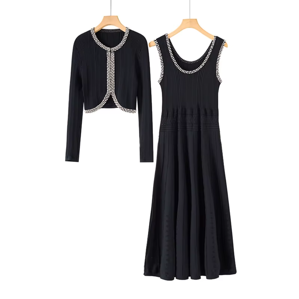 A black two-piece women's outfit set on wooden hangers, featuring a long-sleeve cropped cardigan and a matching sleeveless midi dress with silver rhinestone trim.