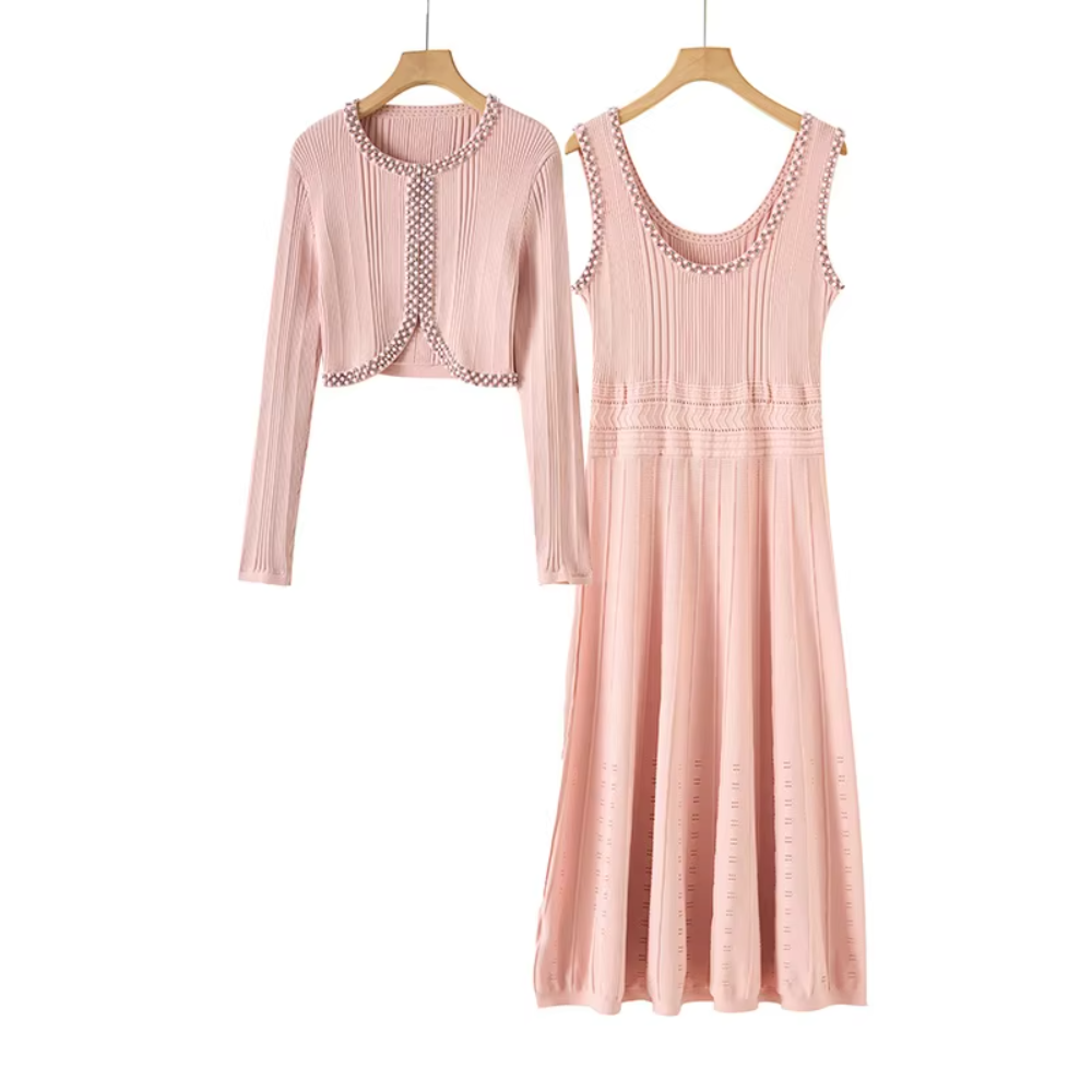 A two-piece women's outfit set in dusty pink, featuring a long-sleeve cropped cardigan and a matching sleeveless midi dress, both hanging on wooden hangers against a plain white background.
