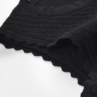 Close-up of a black ribbed knit garment, likely a sweater or top, showing the textured knit pattern and scalloped edge against a white background.