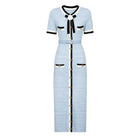 A light blue textured tweed midi dress with black and white trim, featuring a black bow at the collar, gold-tone buttons down the front, and flap pockets with black trim.