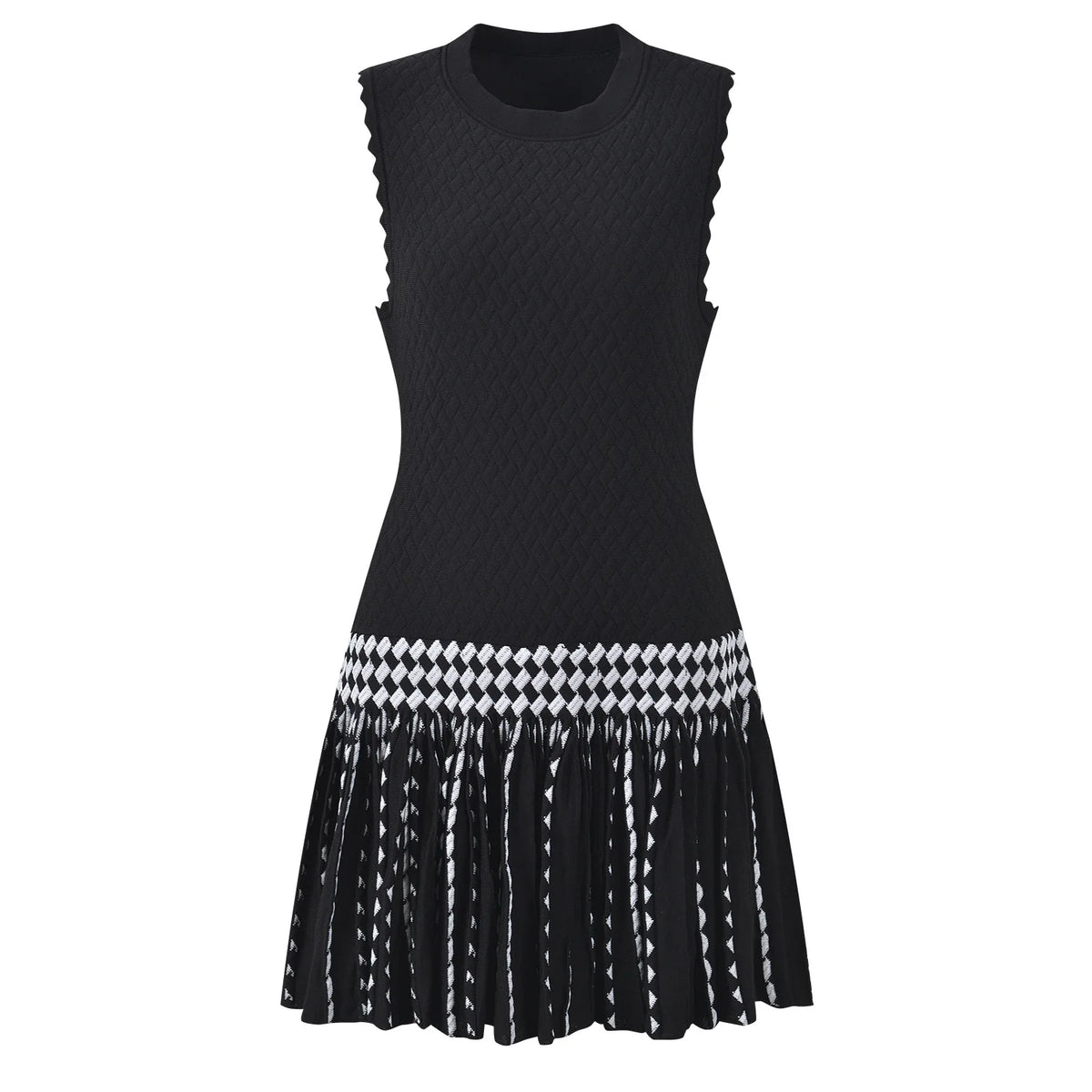 A sleeveless black knit dress with scalloped armholes, a textured bodice, and a pleated skirt featuring a black and white harlequin diamond pattern band and fringe.