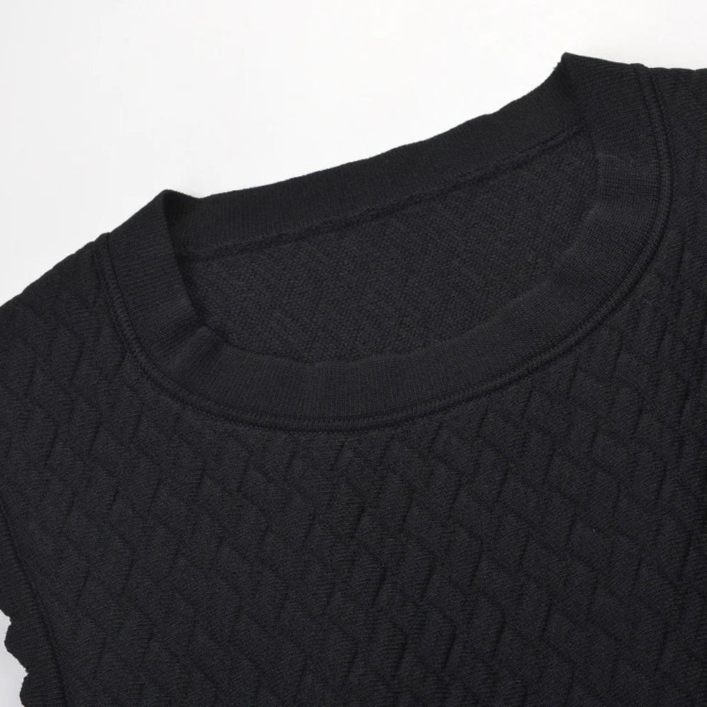 Close-up of a black textured knit top with a crew neck and scalloped sleeve edges, shown against a plain white background.