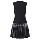 A sleeveless black knit dress with a textured body, scalloped edges, and a flared pleated skirt featuring a black and white geometric pattern and fringe.