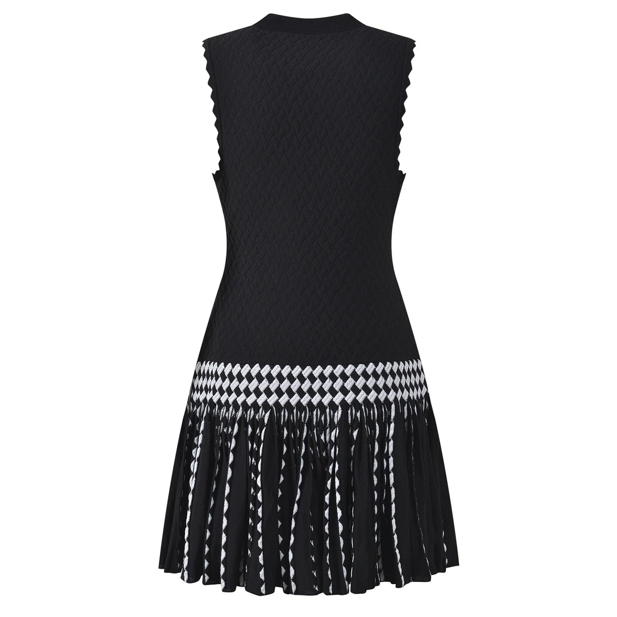 A sleeveless black knit dress with a textured body, scalloped edges, and a flared pleated skirt featuring a black and white geometric pattern and fringe.