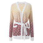 A women's long-sleeve knit cardigan with a white V-neck and tie belt, featuring a chevron pattern that fades from beige and yellow at the top to deep red at the bottom.
