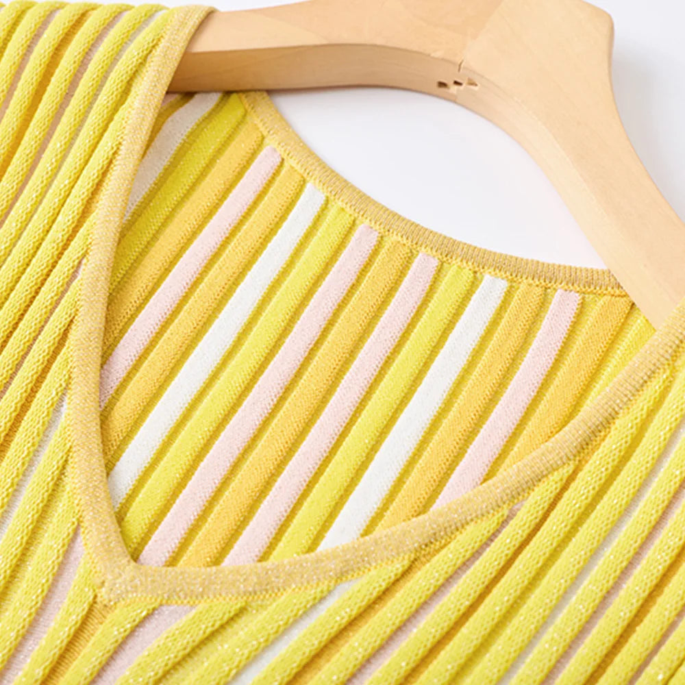 Yellow knit V-neck top with diagonal pink and white stripes, hanging on a wooden hanger against a white background.