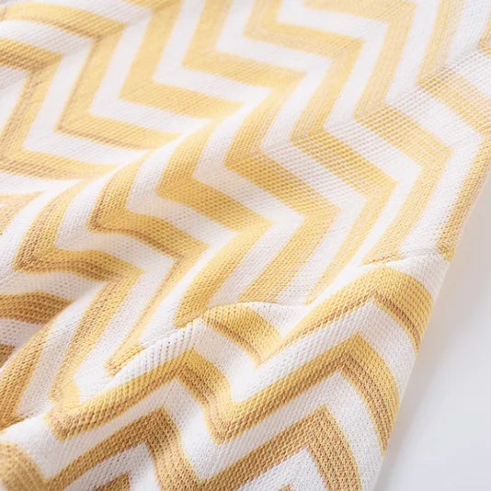 A close-up of a textured knit fabric with a yellow and white chevron pattern.