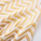 A close-up of a textured knit fabric with a yellow and white chevron pattern.