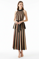 A woman models a sleeveless halter-neck outfit set with vertical stripes in black, brown, and beige. The dress features a structured bodice with a matching self-tie belt at the waist and a flared skirt, shown against a plain white studio background.