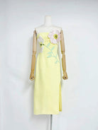 Yellow dress with floral design on a mannequin against a white background