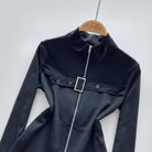 Black bodysuit with a zipper and buckle on a hanger against a white background