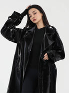 Woman wearing a black glossy coat against a white background