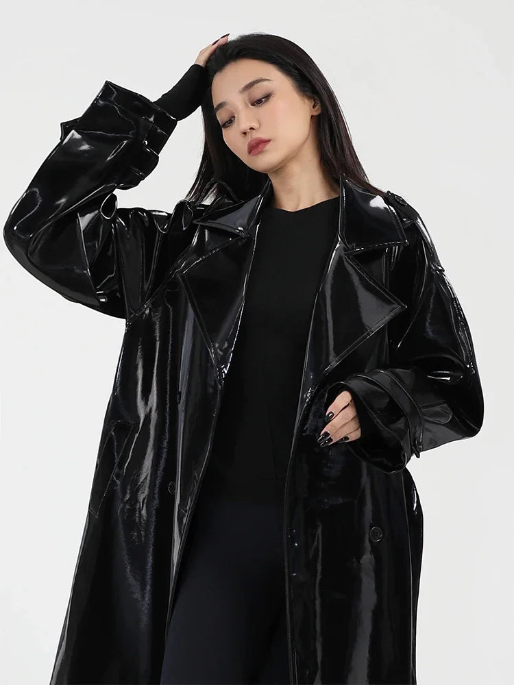 Woman wearing a black glossy coat against a white background