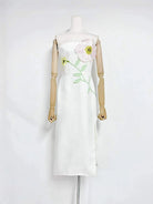 White dress with floral embroidery on a mannequin against a white background